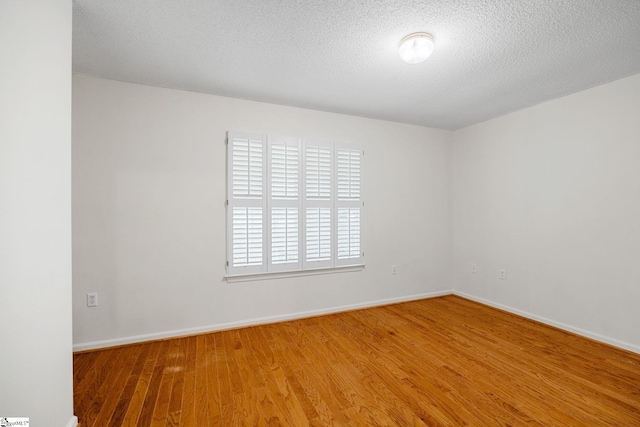 empty room with wood finished floors, baseboards, and a textured ceiling