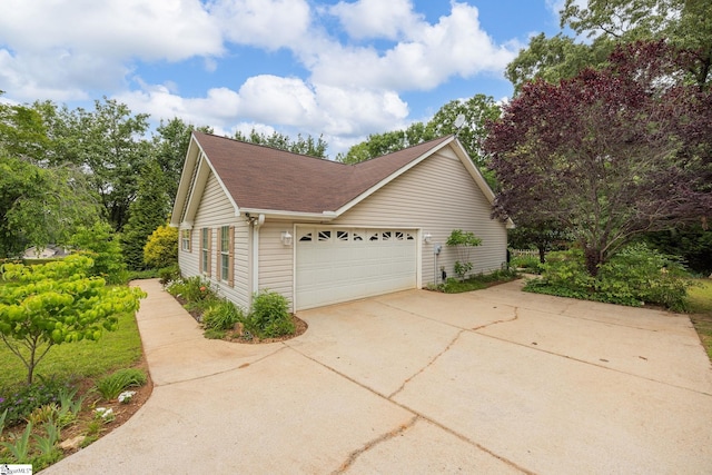 view of side of home featuring a garage and a shingled roof