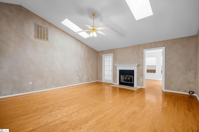unfurnished living room with a skylight, wood finished floors, healthy amount of natural light, and high vaulted ceiling