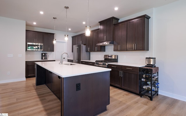 kitchen with appliances with stainless steel finishes, a sink, under cabinet range hood, dark brown cabinets, and recessed lighting