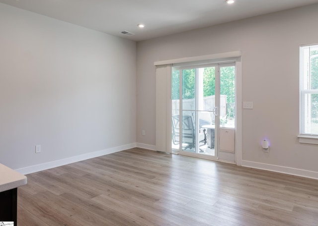 spare room featuring plenty of natural light, light wood-style flooring, baseboards, and recessed lighting