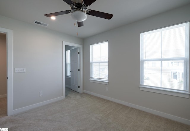 unfurnished bedroom with light colored carpet, baseboards, ceiling fan, and ensuite bath