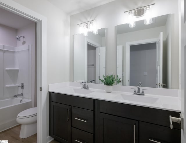 bathroom with toilet, washtub / shower combination, double vanity, and wood finished floors