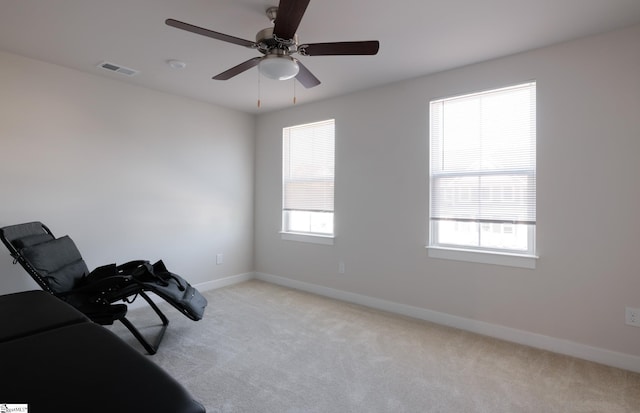 living area with light colored carpet, baseboards, and ceiling fan