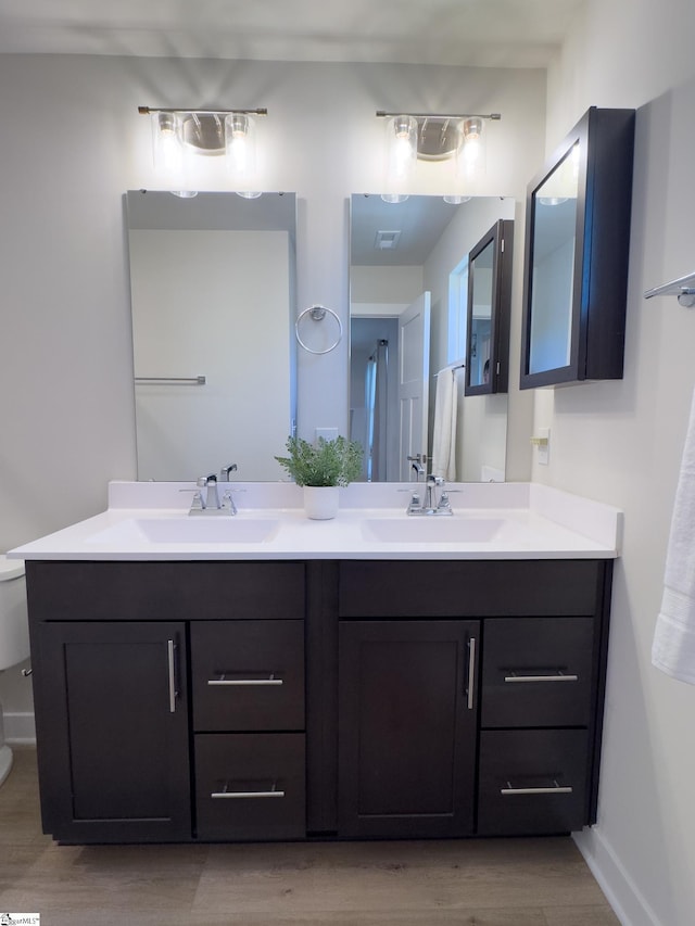 full bathroom with wood finished floors, double vanity, and baseboards