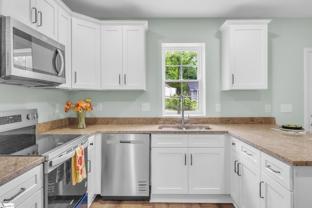 kitchen with stainless steel appliances, a sink, and white cabinetry