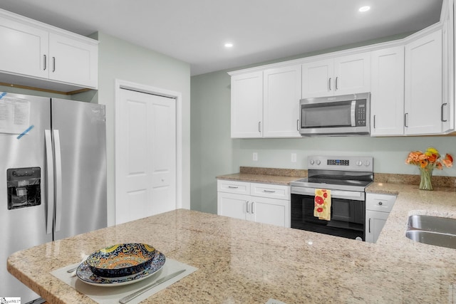 kitchen with appliances with stainless steel finishes, recessed lighting, white cabinetry, and light stone counters