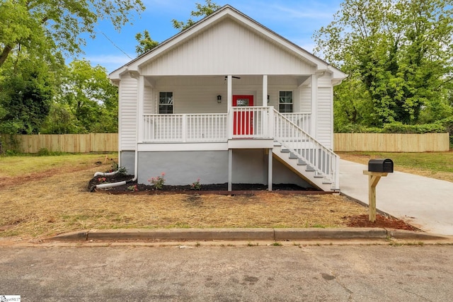 bungalow-style house featuring covered porch, fence, and stairs