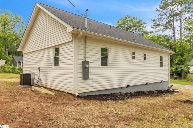 view of side of home with cooling unit and a shingled roof