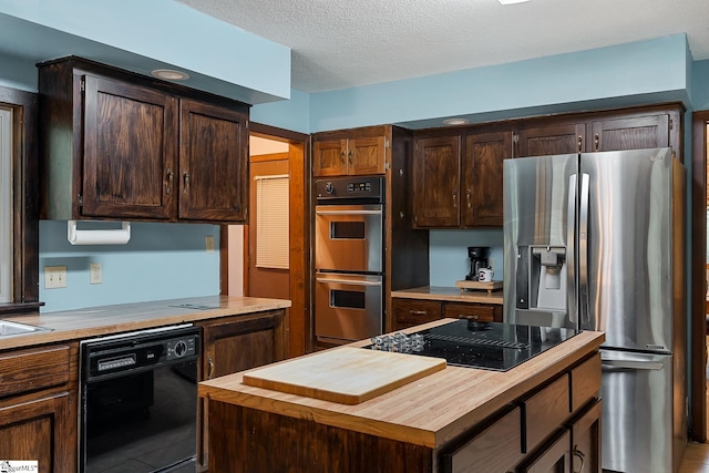 kitchen featuring black appliances, wood counters, a center island, dark brown cabinetry, and a textured ceiling