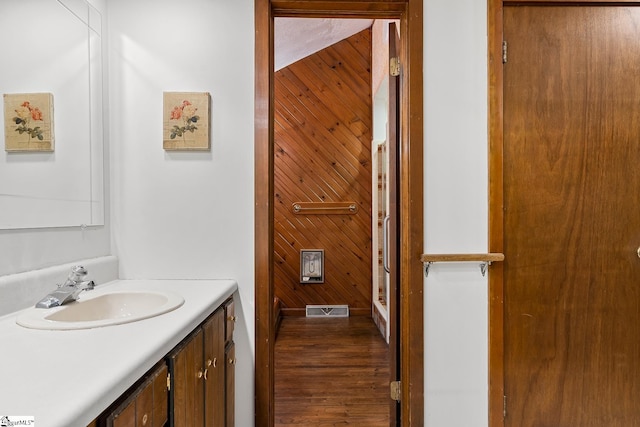 bathroom with wood finished floors, vanity, and wood walls