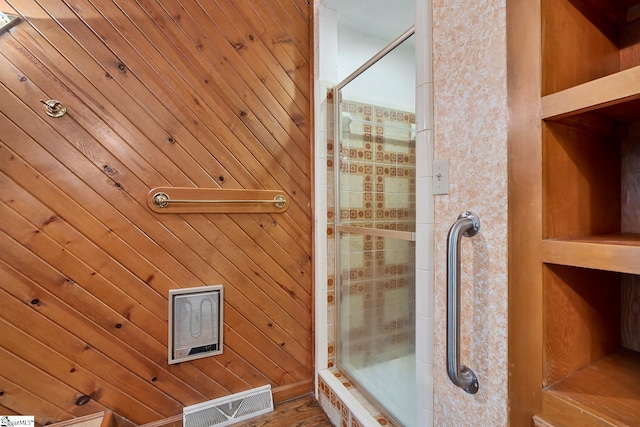 full bath featuring tiled shower and wooden walls