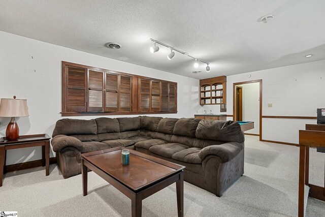 living area with light colored carpet, baseboards, track lighting, and wet bar