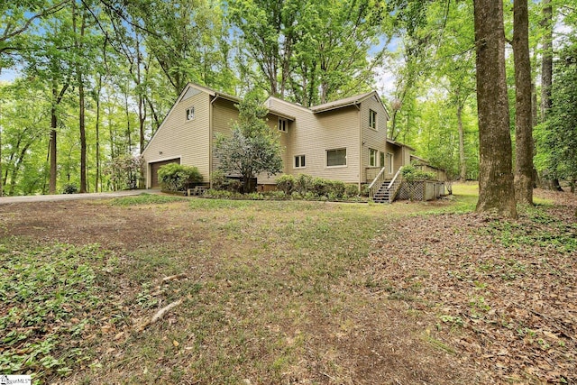 view of home's exterior featuring concrete driveway and stairs