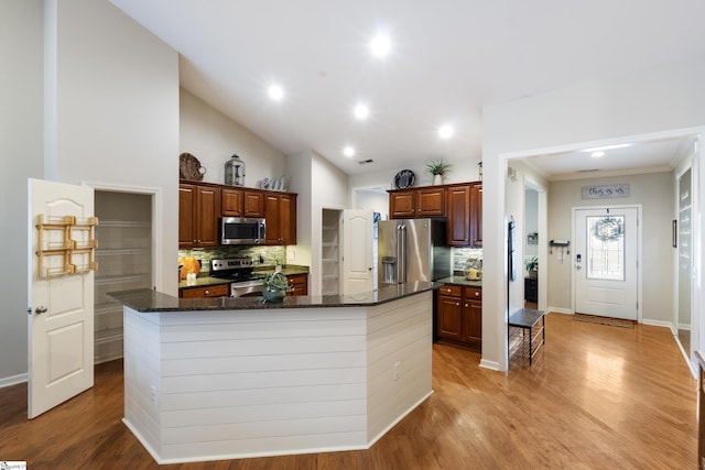 208 Medoc Ln, Moore, SC 29369 - kitchen with appliances with stainless steel finishes, tasteful backsplash, a center island with sink, light wood finished floors, and ornamental molding