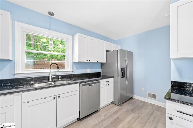 222 Woodview Ave, Spartanburg, SC 29306 - kitchen featuring appliances with stainless steel finishes, a sink, light wood-style flooring, white cabinets, and dark stone countertops
