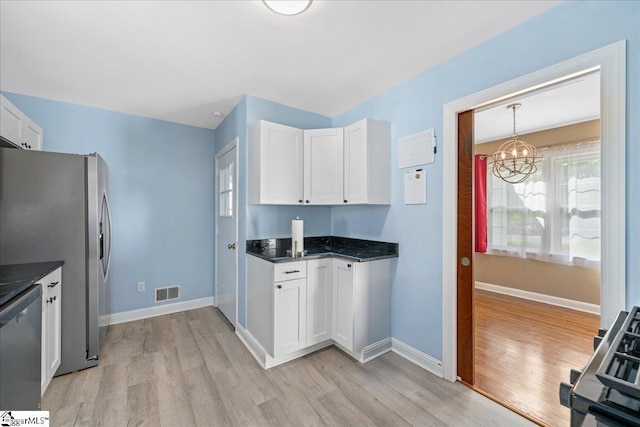 222 Woodview Ave, Spartanburg, SC 29306 - kitchen with light wood finished floors, appliances with stainless steel finishes, a chandelier, white cabinets, and baseboards