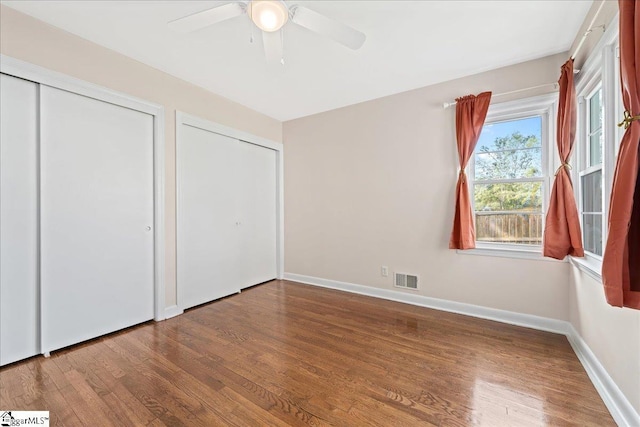 222 Woodview Ave, Spartanburg, SC 29306 - unfurnished bedroom featuring wood finished floors, multiple closets, baseboards, and ceiling fan