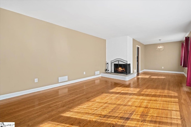 222 Woodview Ave, Spartanburg, SC 29306 - unfurnished living room featuring wood finished floors, a chandelier, a multi sided fireplace, and baseboards