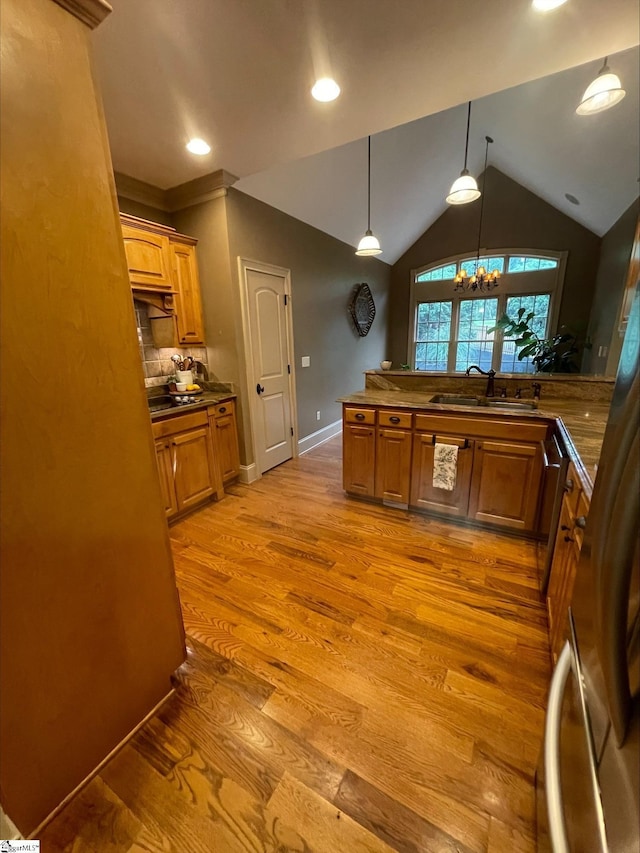 kitchen featuring a sink, dark countertops, brown cabinets, a chandelier, and lofted ceiling