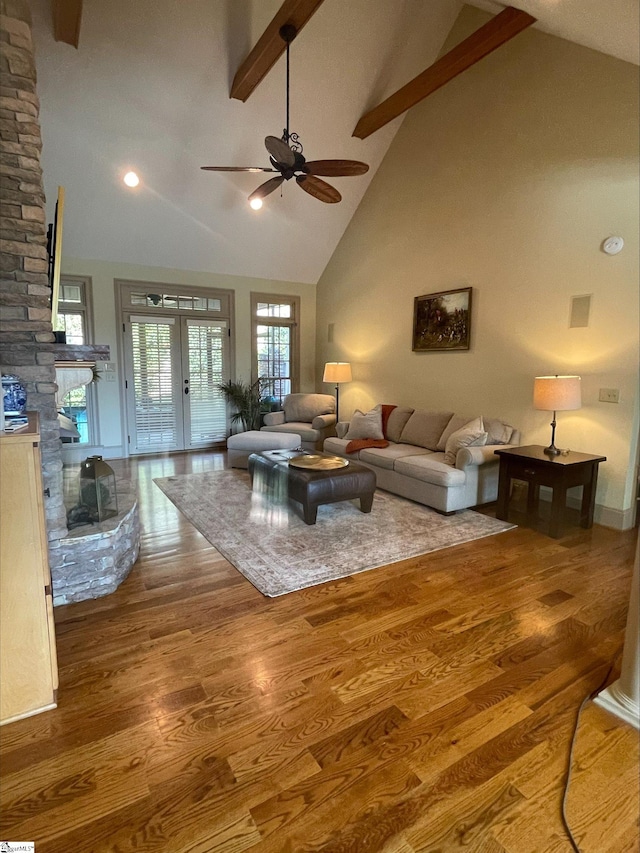living area featuring high vaulted ceiling, wood finished floors, beam ceiling, ceiling fan, and a fireplace