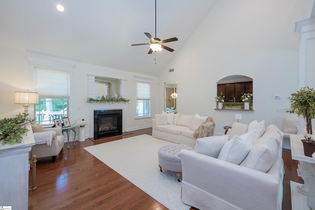 living room with healthy amount of natural light, ceiling fan, wood finished floors, high vaulted ceiling, and a fireplace with flush hearth