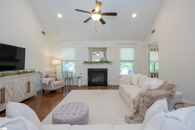 living area featuring high vaulted ceiling, ceiling fan, a fireplace with flush hearth, dark wood-style flooring, and baseboards
