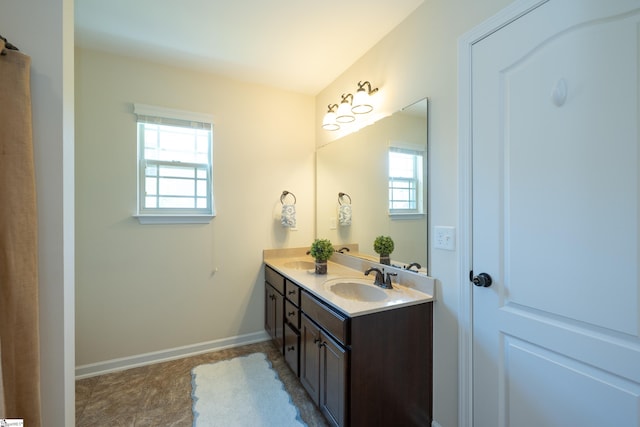 full bathroom with baseboards and double vanity