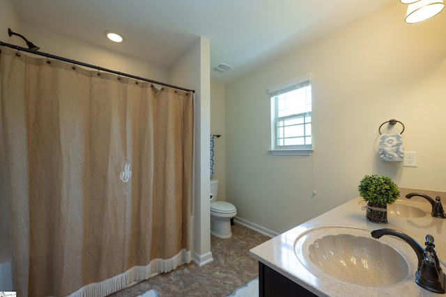 full bathroom with toilet, double vanity, and baseboards