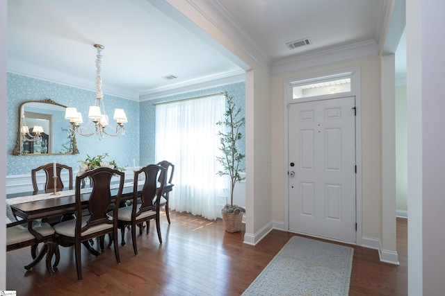 entrance foyer with a chandelier, wallpapered walls, crown molding, dark wood finished floors, and baseboards