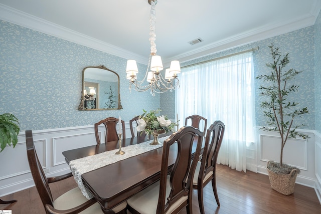 dining room featuring a chandelier, ornamental molding, wood-type flooring, a wainscoted wall, and wallpapered walls