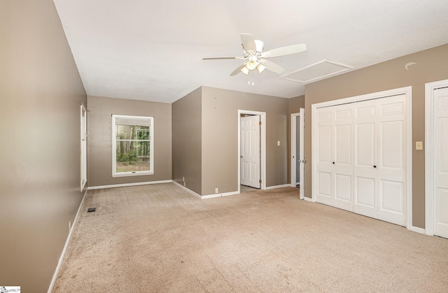 unfurnished bedroom with attic access, light carpet, baseboards, and a ceiling fan