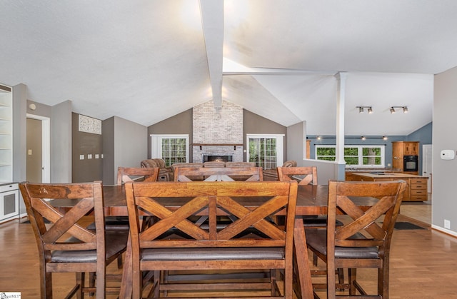 dining area featuring wood finished floors, vaulted ceiling, and a fireplace