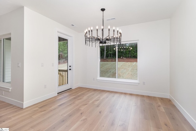 unfurnished dining area with light wood-style floors, a chandelier, and baseboards
