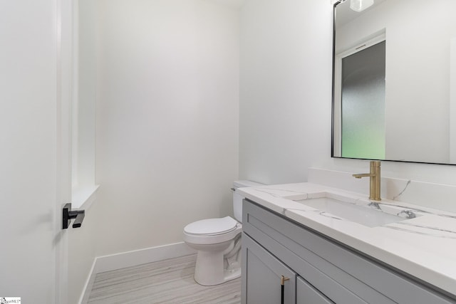 half bathroom featuring toilet, vanity, and baseboards