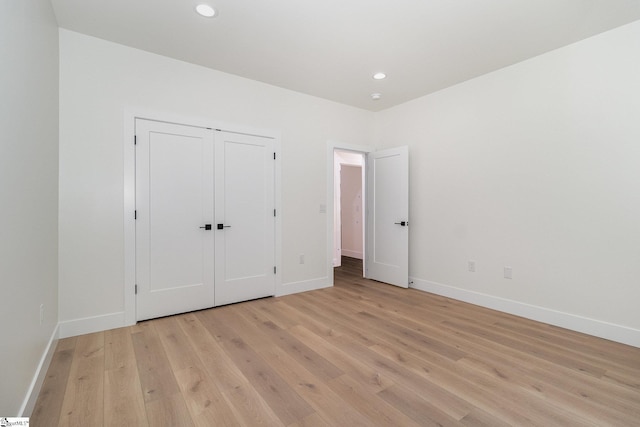 unfurnished bedroom featuring baseboards, light wood-style flooring, recessed lighting, and a closet