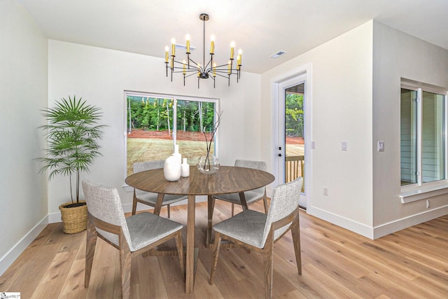 dining area with a chandelier, healthy amount of natural light, baseboards, and light wood-style flooring