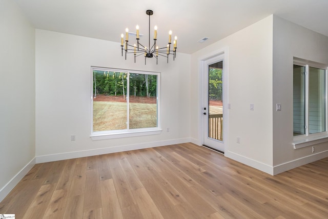 unfurnished dining area with a chandelier, baseboards, and light wood-type flooring