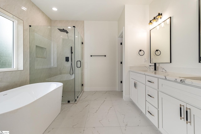 bathroom with vanity, marble finish flooring, a shower stall, a soaking tub, and baseboards