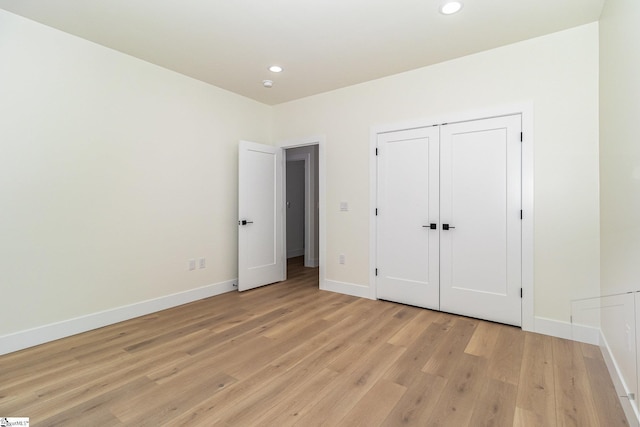 unfurnished bedroom featuring baseboards, light wood-type flooring, recessed lighting, and a closet