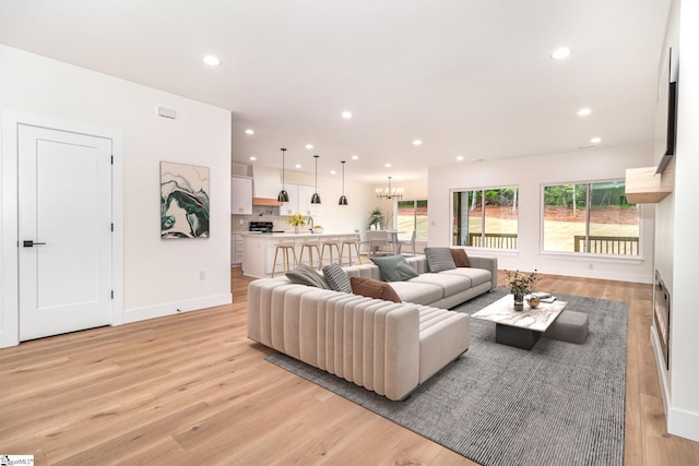 living area featuring light wood-style flooring, recessed lighting, baseboards, and a chandelier