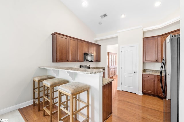11 Penrith Ct, Simpsonville, SC 29681 - kitchen featuring black microwave, freestanding refrigerator, a peninsula, light stone counters, and a kitchen bar