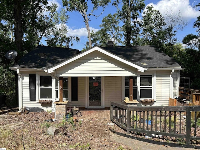 view of front of property with roof with shingles, a chimney, and a porch