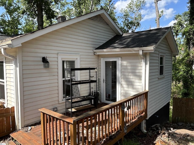 back of house featuring a shingled roof, a deck, and fence