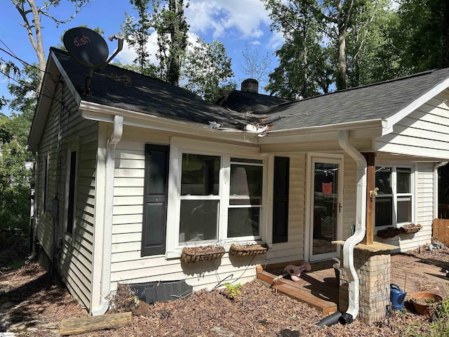 view of property exterior featuring a chimney and roof with shingles