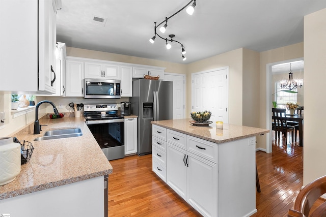 26 Willow Oak Ct, Simpsonville, SC 29681 - kitchen featuring appliances with stainless steel finishes, a sink, a chandelier, white cabinetry, and light wood finished floors