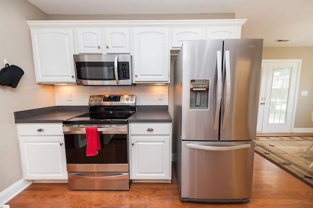 kitchen with stainless steel appliances, dark countertops, baseboards, and white cabinets