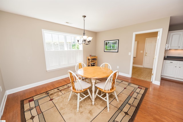 dining space featuring a chandelier, light wood finished floors, and baseboards