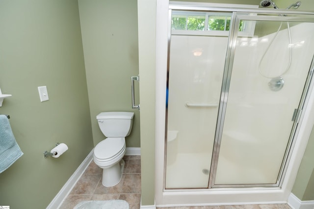 bathroom with baseboards, a shower stall, and toilet