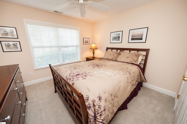 bedroom featuring light colored carpet, baseboards, and a ceiling fan